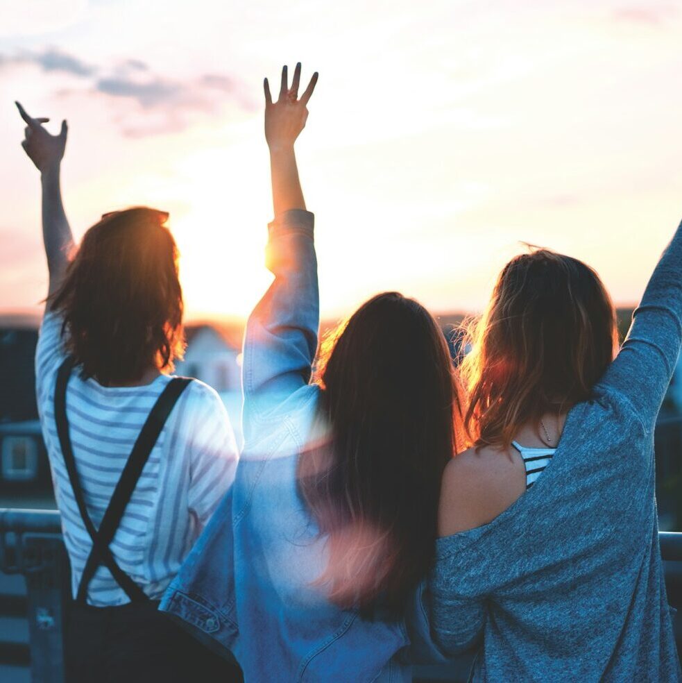 photo of three women lifting there hands 